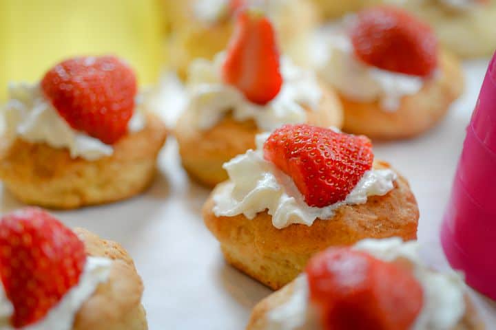 Close-up of strawberry shortcakes with whipped cream on a blurred background.